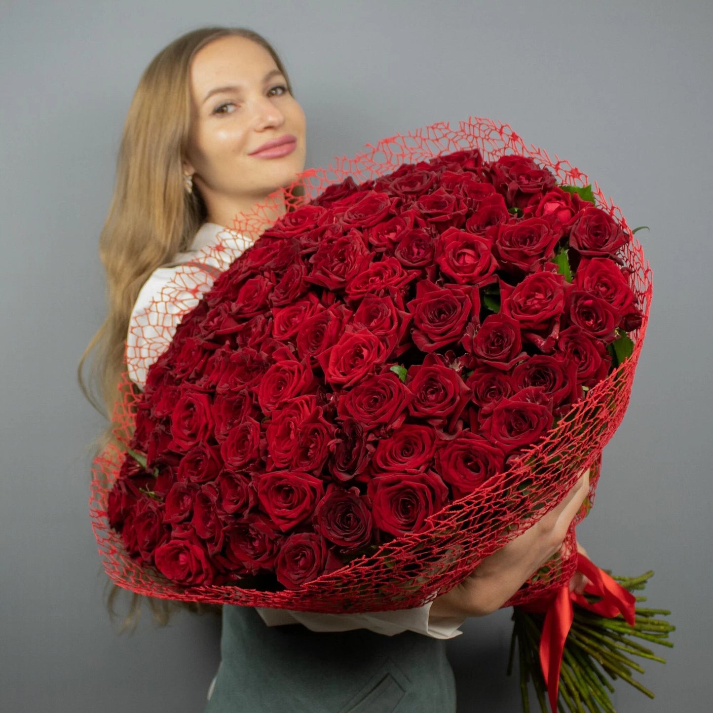 Woman holding a 350 naomi red roses luxury bouquet