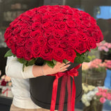Large hat box bouquet of red roses held by a person