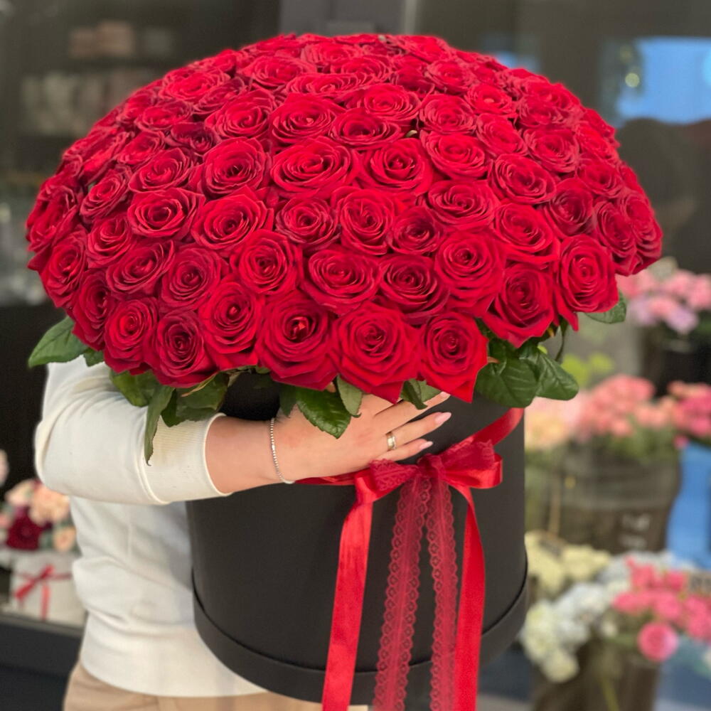Large hat box bouquet of red roses held by a person