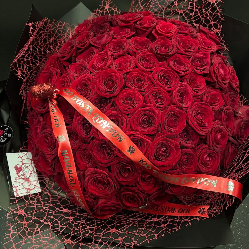 Bouquet of luxury 100 red roses with a red ribbon on a black background